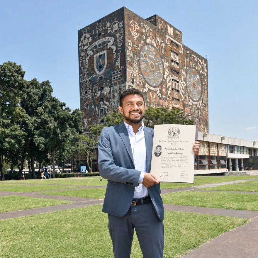 Alan Farid Badager con su título de Licenciado en Psicología frente a la Biblioteca Central de la UNAM